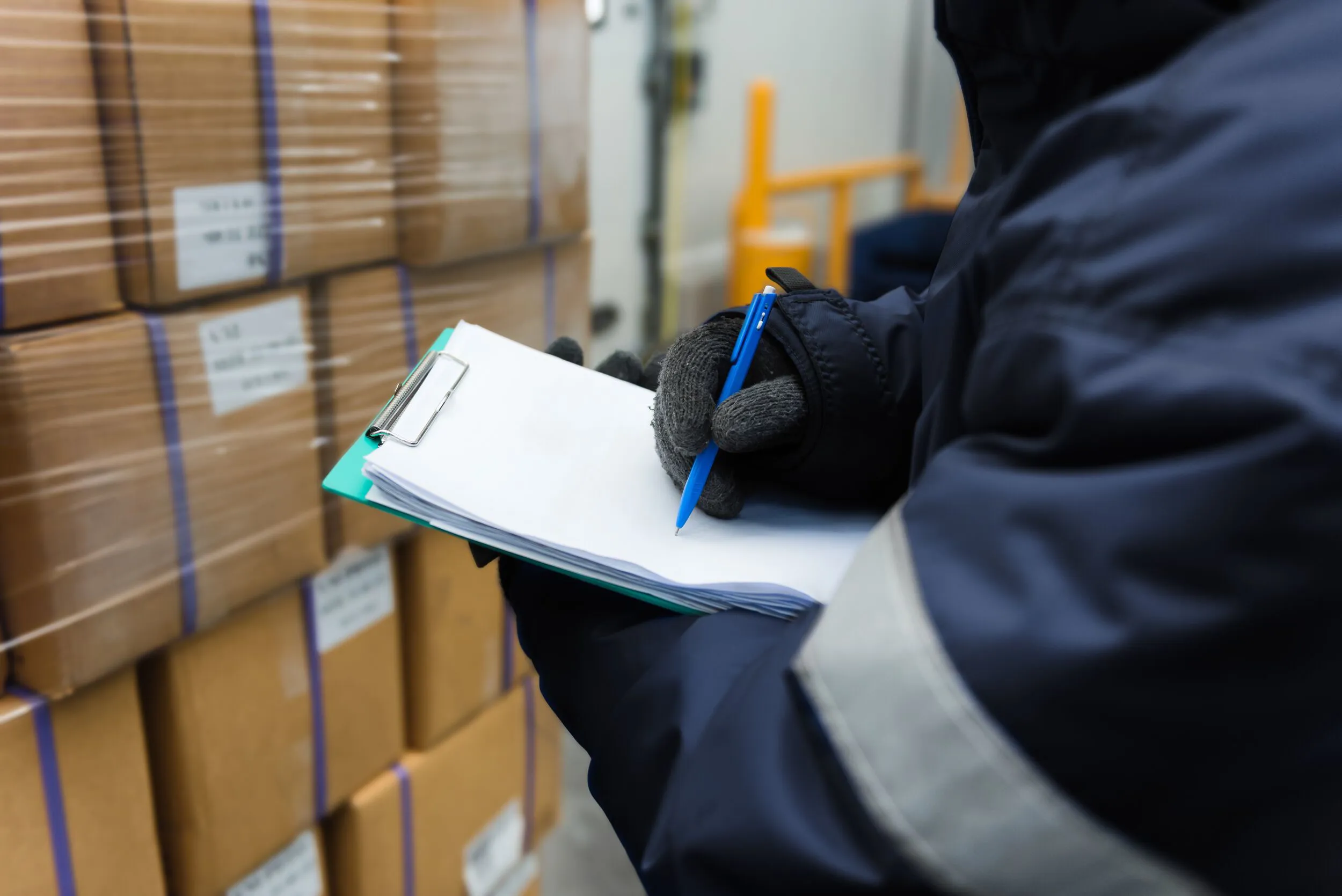Closeup shooting hand of worker with clipboard checking goods in freezing room or warehouse.